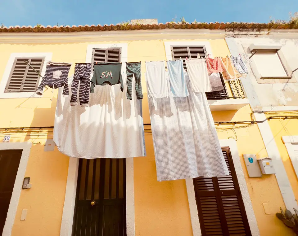 Vibrant laundry hanging on a yellow townhouse in Seixal, Portugal.