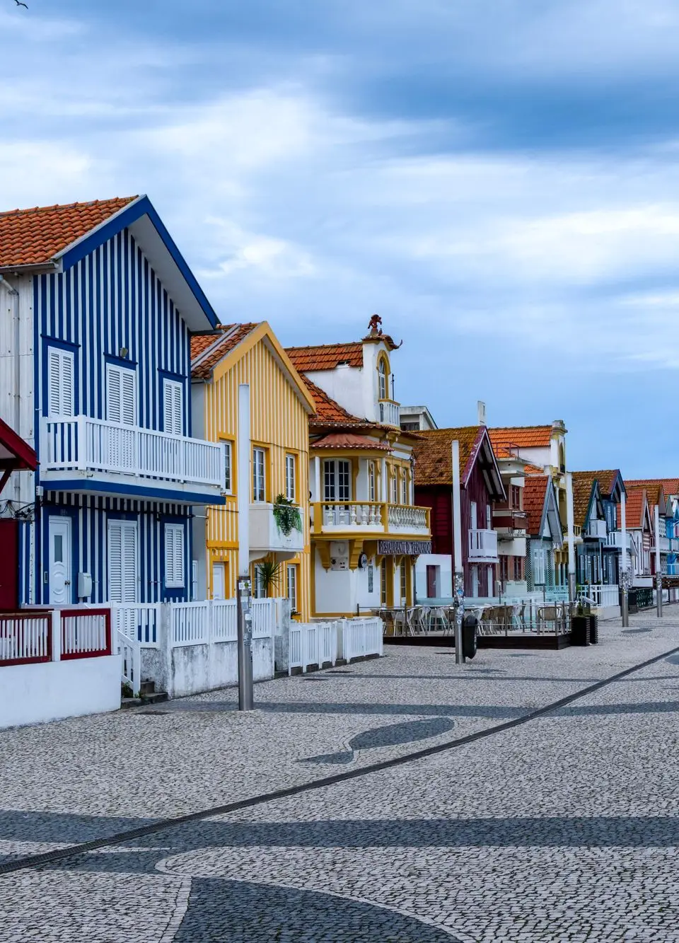 Vibrant striped cottages lining a coastal promenade in Costa Nova, Portugal.
