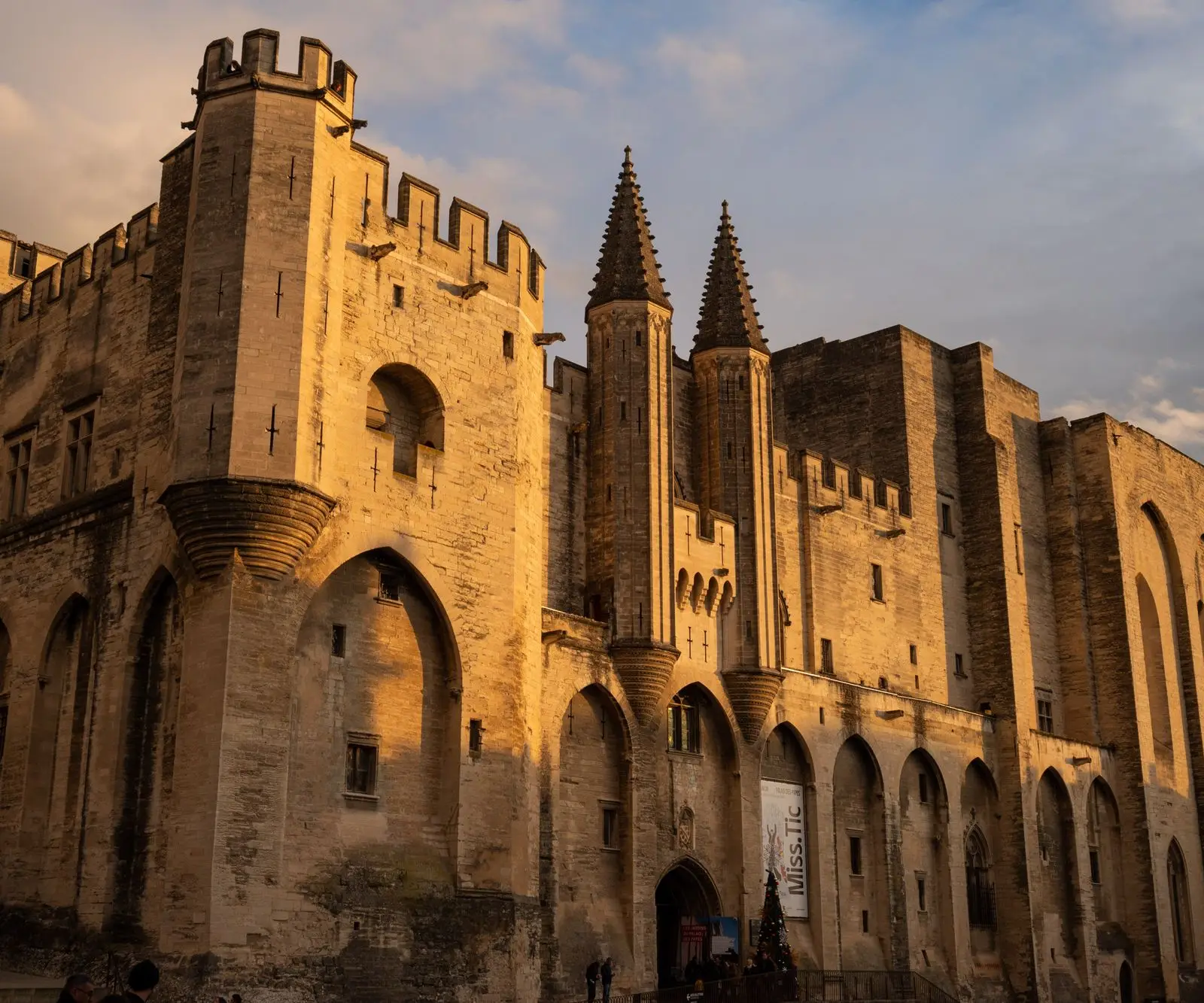 The stunning Papal Palace in Avignon, France, illuminated by the warm glow of the sunset.