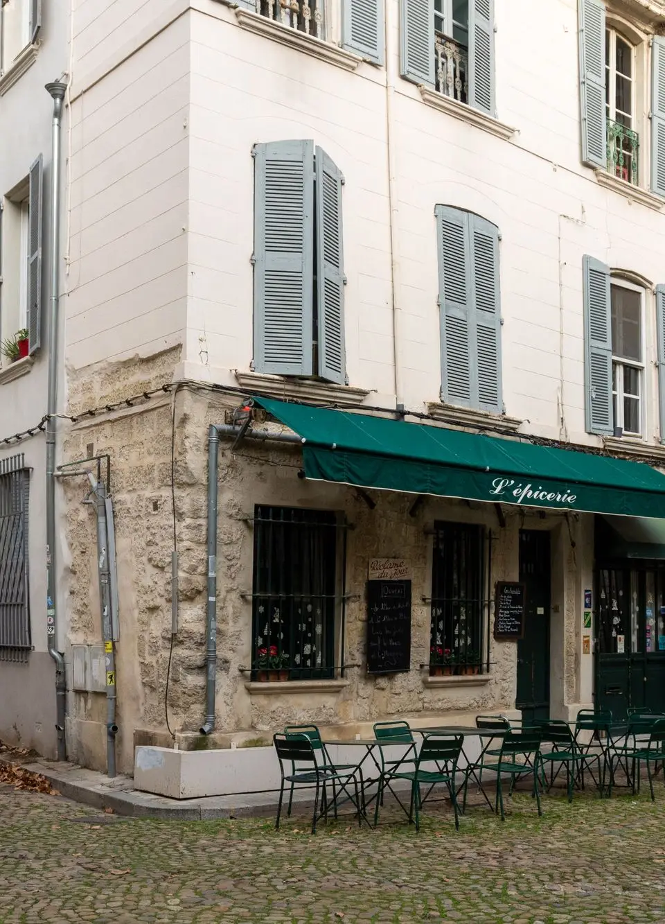 Quaint street corner with a cozy cafe in Avignon, showcasing timeless European architecture.