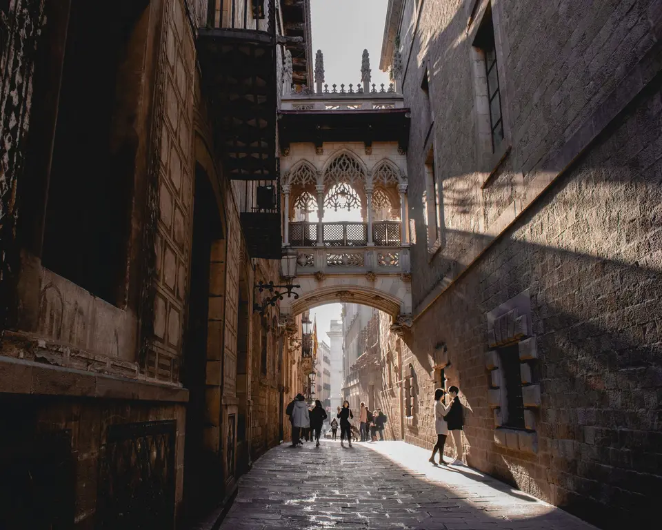 People walking under Pont del Bisbe in Barcelona's Gothic Quarter.