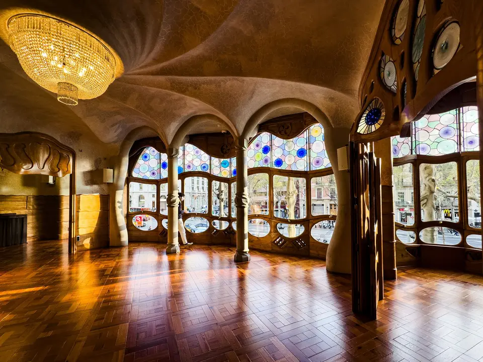 Stunning interior of Casa Batlló with Gaudí's iconic design, stained glass, and chandelier.