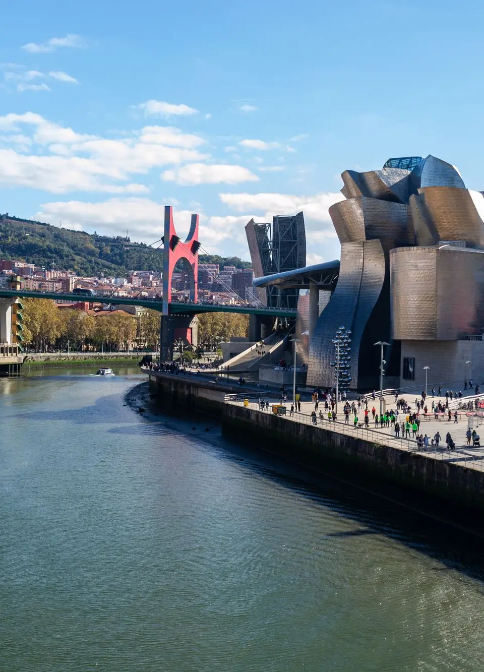 A stunning view of Guggenheim Museum Bilbao alongside a scenic river and urban landscape.