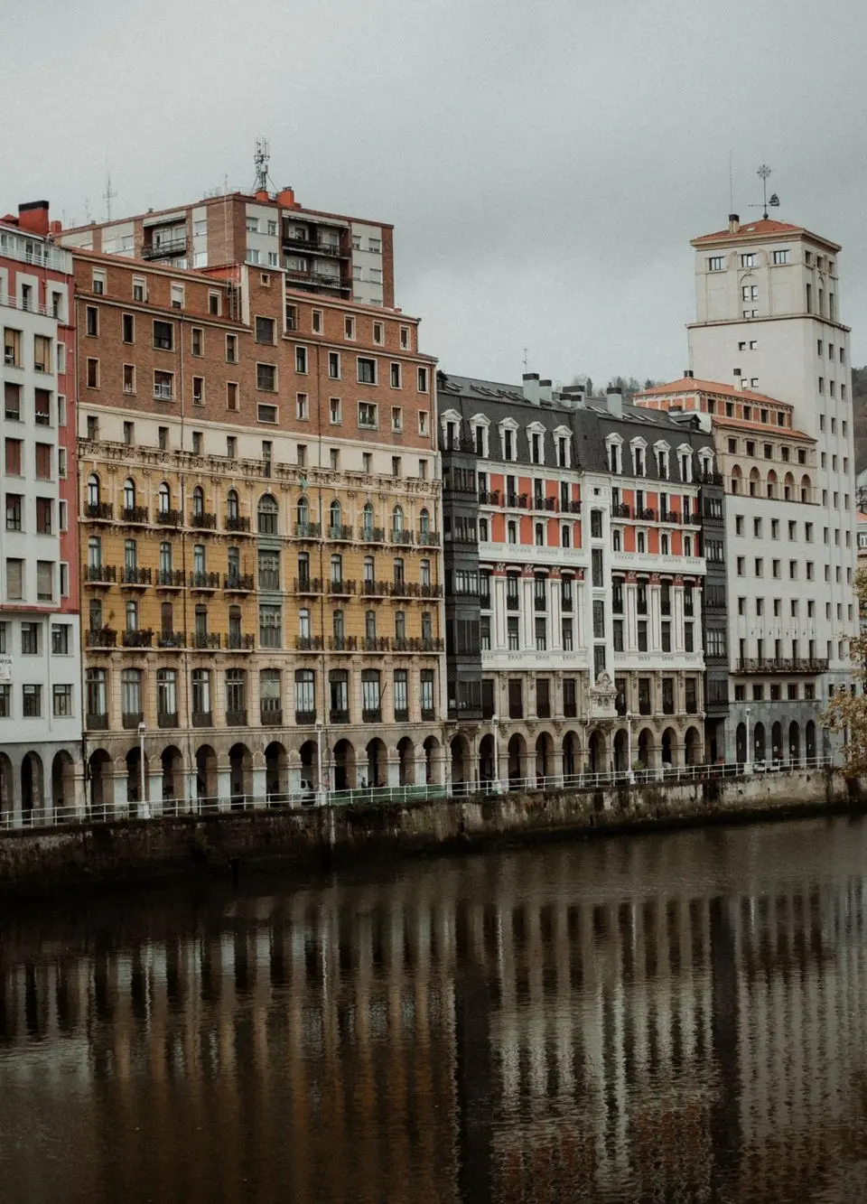 Charming riverside buildings in Bilbao capturing classic architecture with autumn reflections.