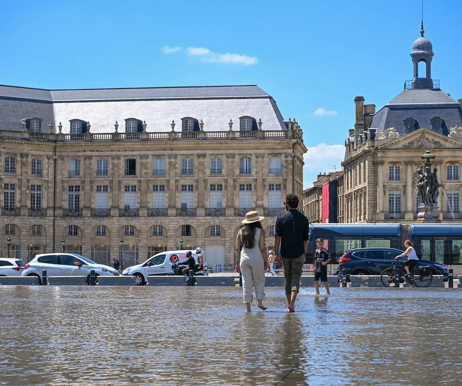 People enjoying a sunny day at Place de la Bourse in Bordeaux, France, with the iconic water mirror.