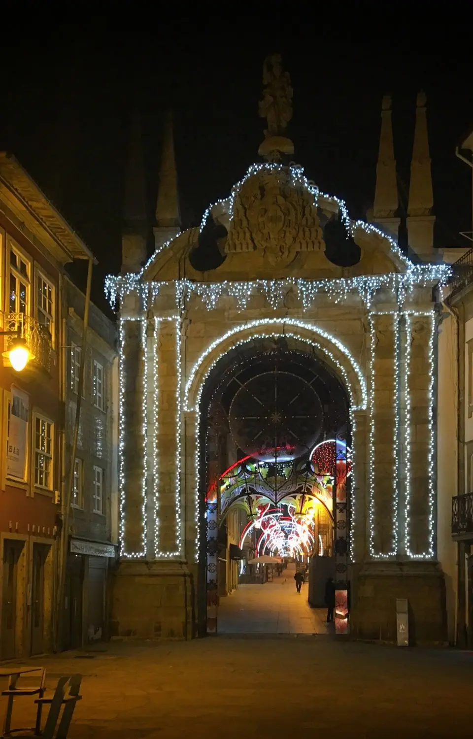 Night scene of the illuminated Arco da Porta Nova in Braga, Portugal, showcasing festive lights.