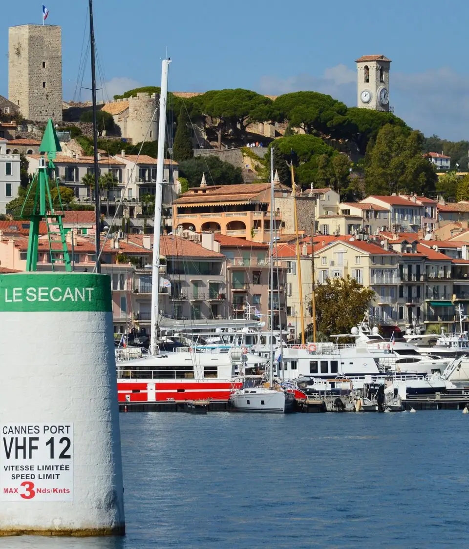 Picturesque Cannes harbor with luxury yachts and historic architecture on a sunny day.