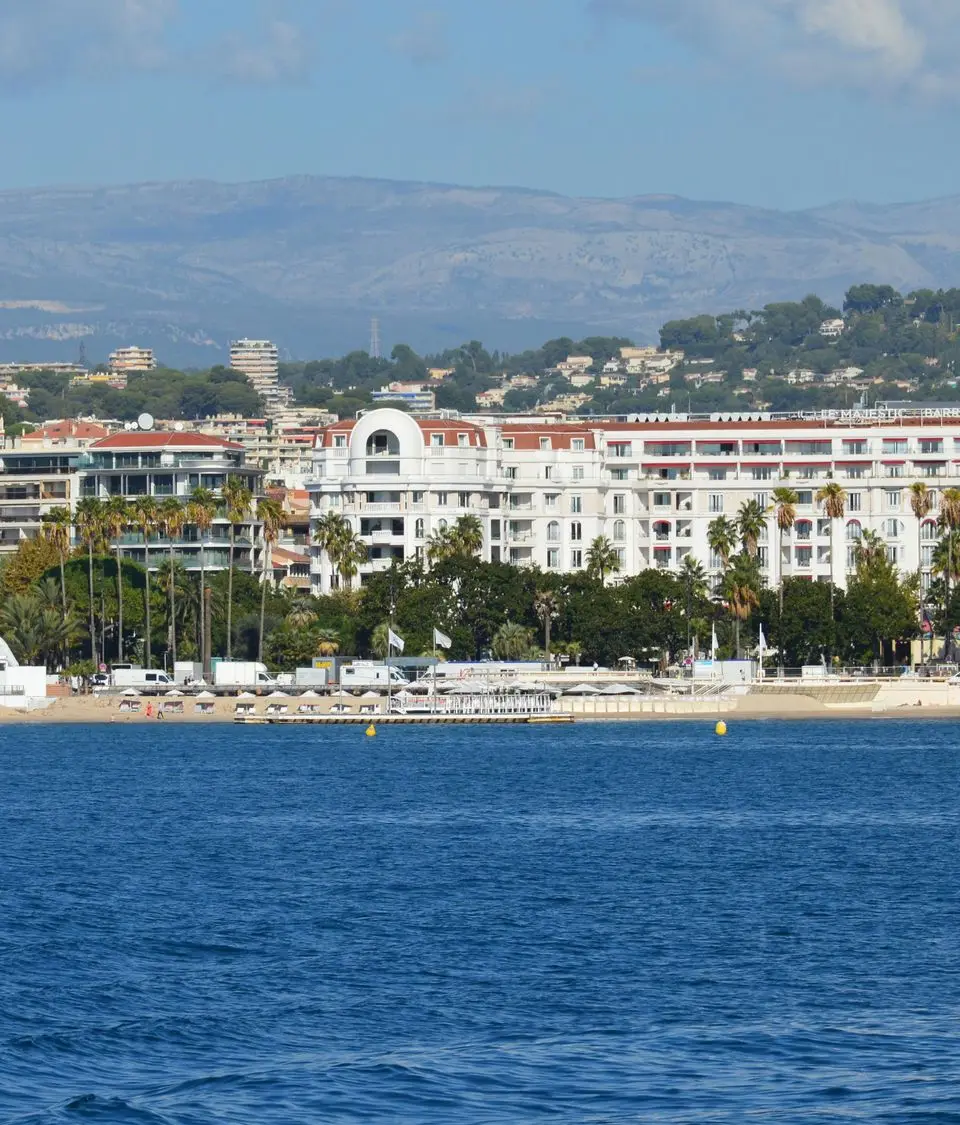 A beautiful view of Cannes coastline showcasing buildings and clear blue sea under a sunny sky.