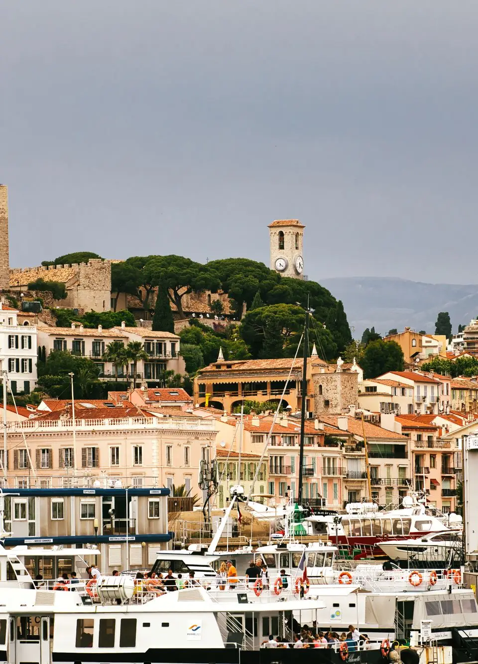 Beautiful day at Cannes harbor with yachts and view of Fort Royal in France.
