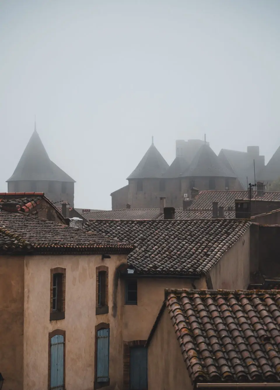 Foggy morning over Carcassonne's historic rooftops and towers in Occitanie, France.