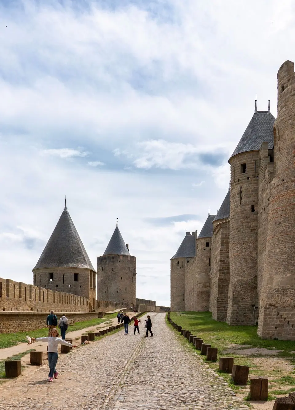 A view of the historic towers and walls of Carcassonne, France, with tourists exploring.