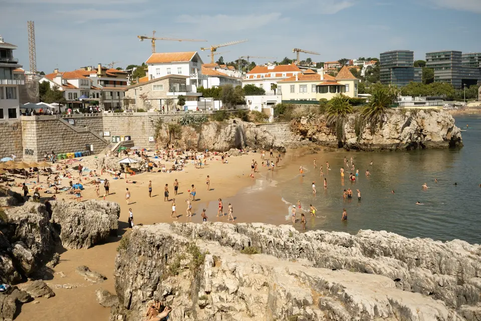 A lively beach scene in Cascais, Portugal with people enjoying the sun and sea.