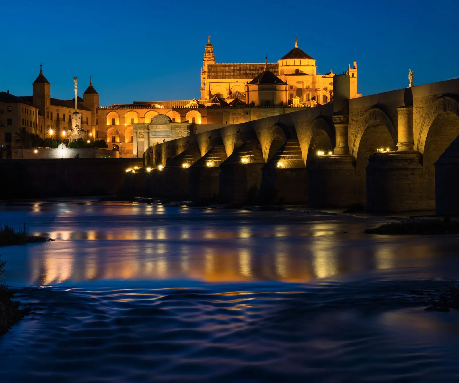 Stunning view of Córdoba's Roman Bridge and Mosque-Cathedral illuminated at night.