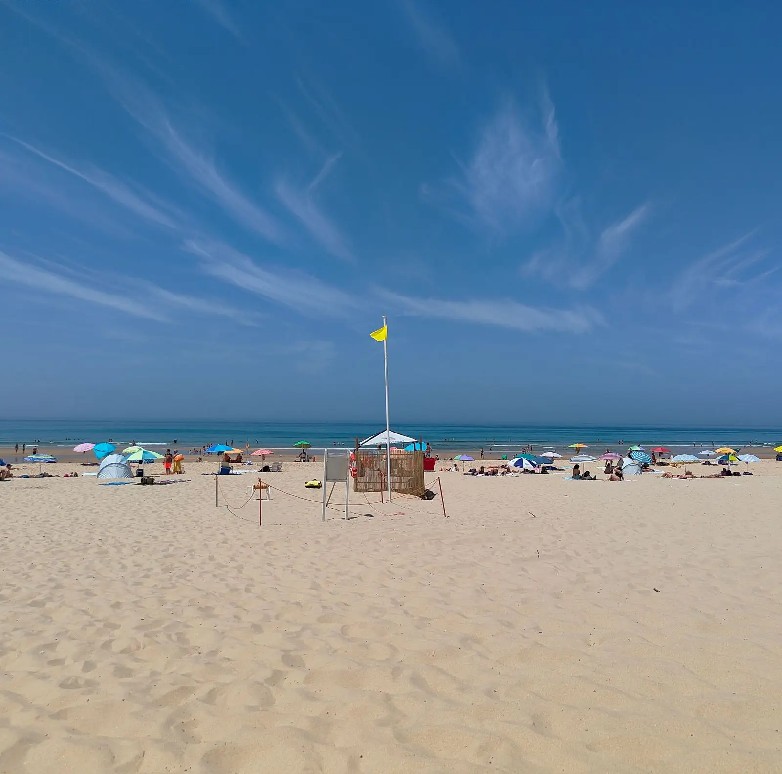 Beautiful sunny day at Costa da Caparica, Portugal, with vibrant beach umbrellas and a clear blue sky.