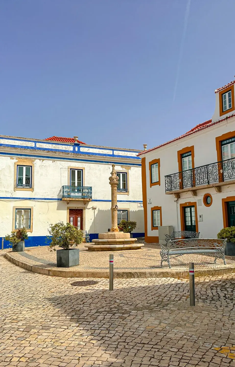 Picturesque town square in Ericeira, Portugal featuring historic architecture under a clear summer sky.