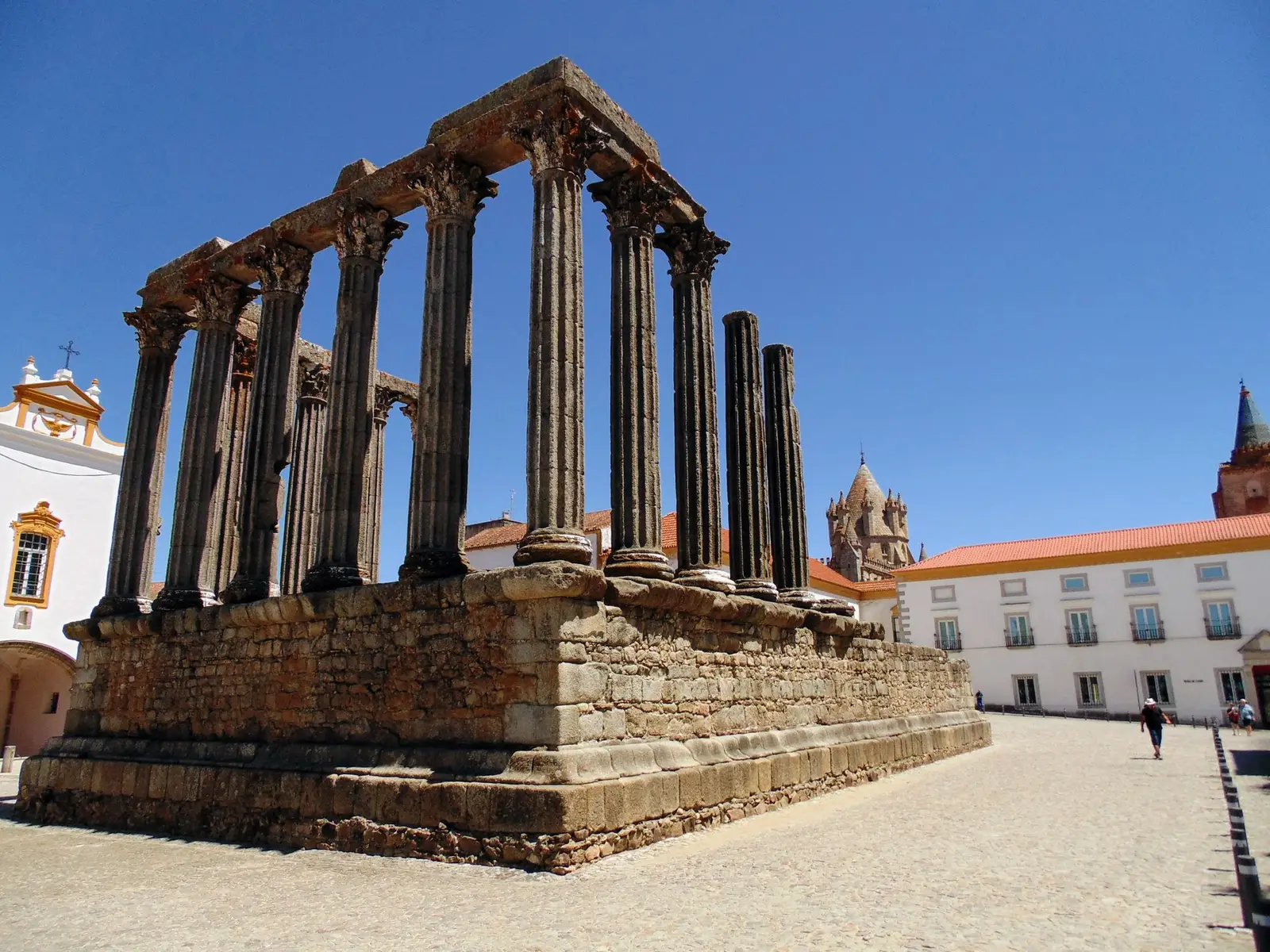 Ancient Roman temple ruins in Évora, Portugal, highlighted against a vivid blue sky.