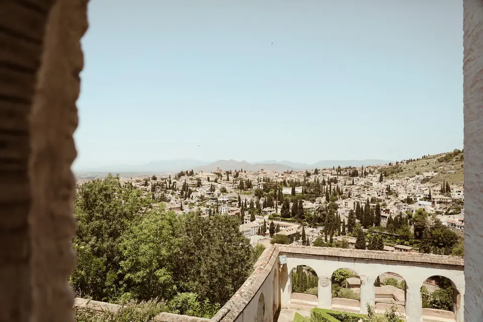 Panoramic view of Granada cityscape framed by historic architecture under a summer sky.