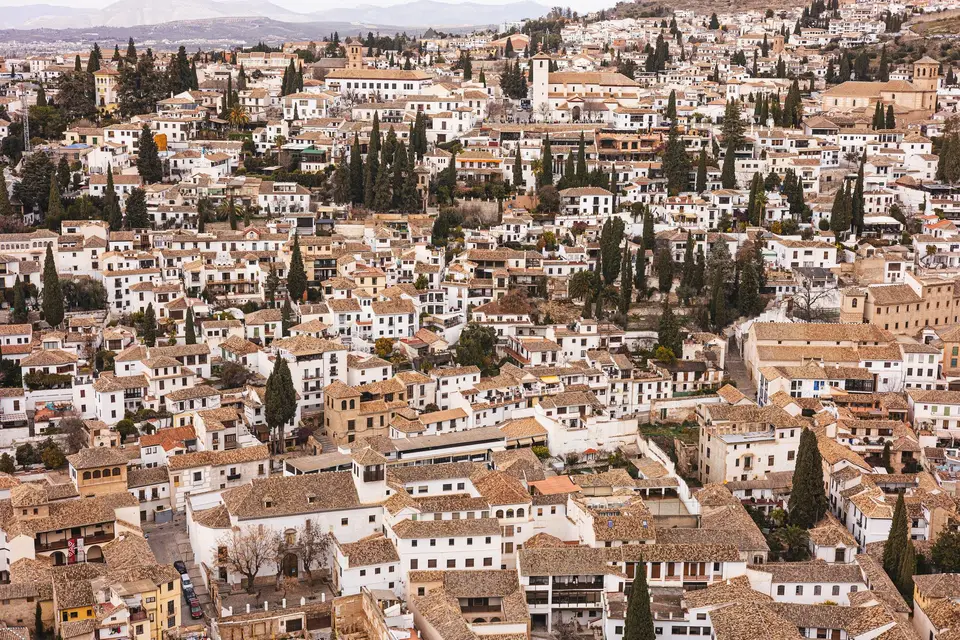 Scenic aerial view of Granada's old town with traditional architecture and cypress trees.