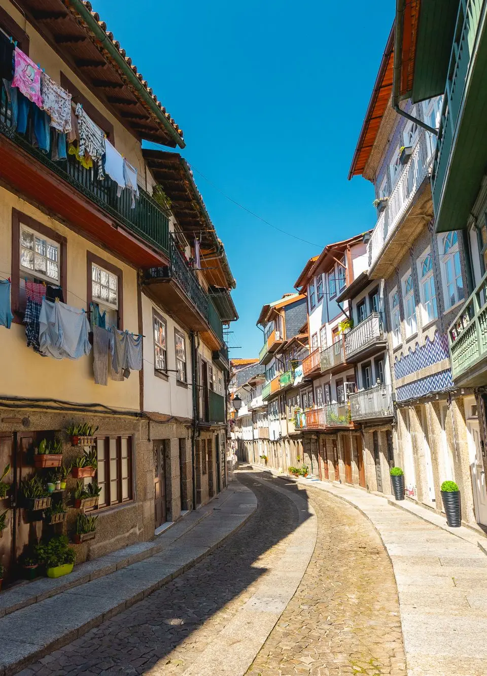 Picturesque view of narrow cobblestone street with colorful architecture in Guimarães, Portugal.