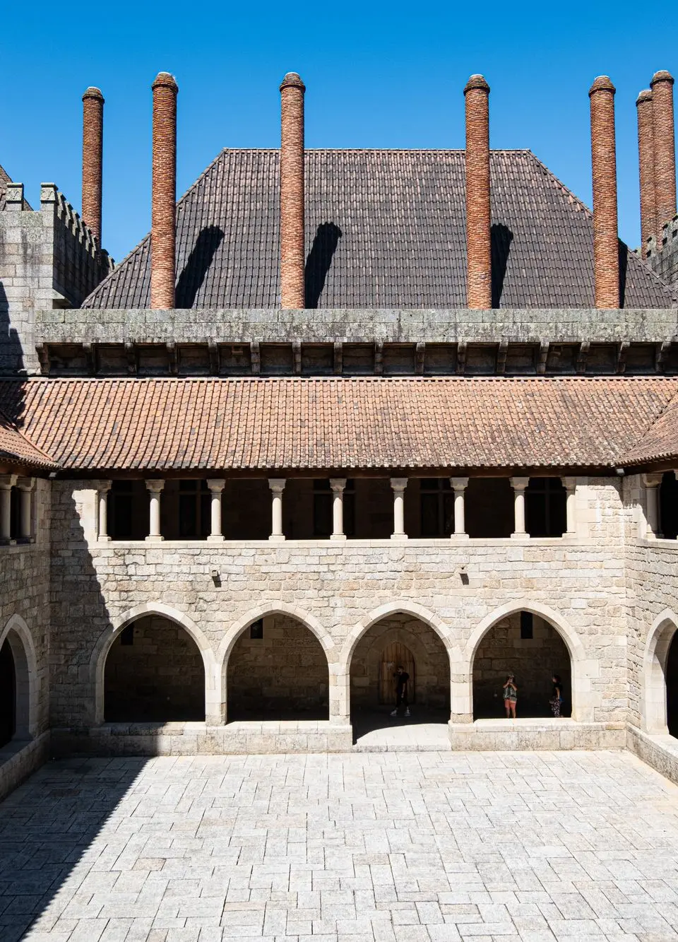 Historic courtyard in Guimaraes Palace, showing medieval architecture against a clear blue sky.