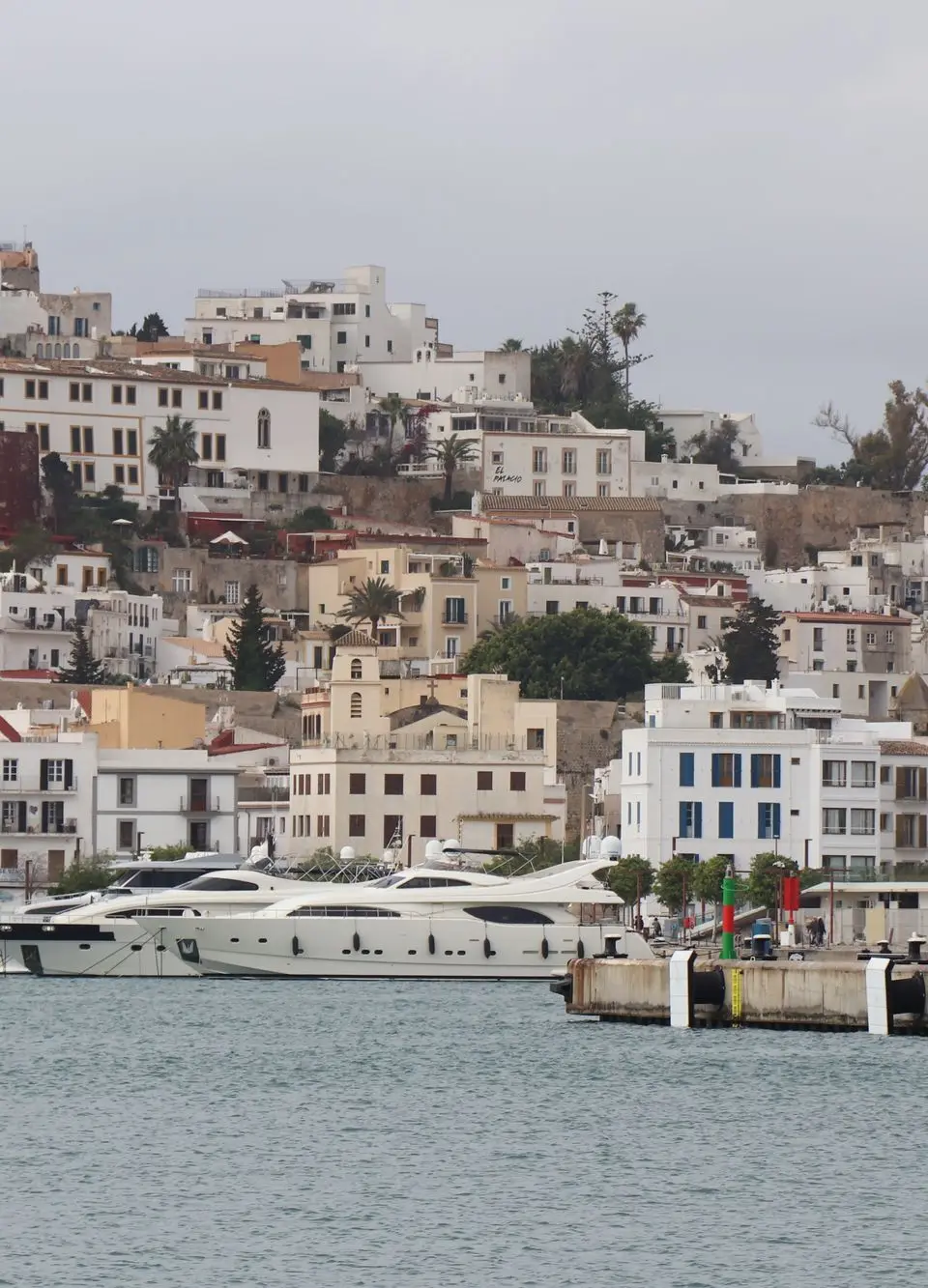 Panoramic view of Ibiza's old town architecture and luxury yachts in the marina, Balearic Islands.