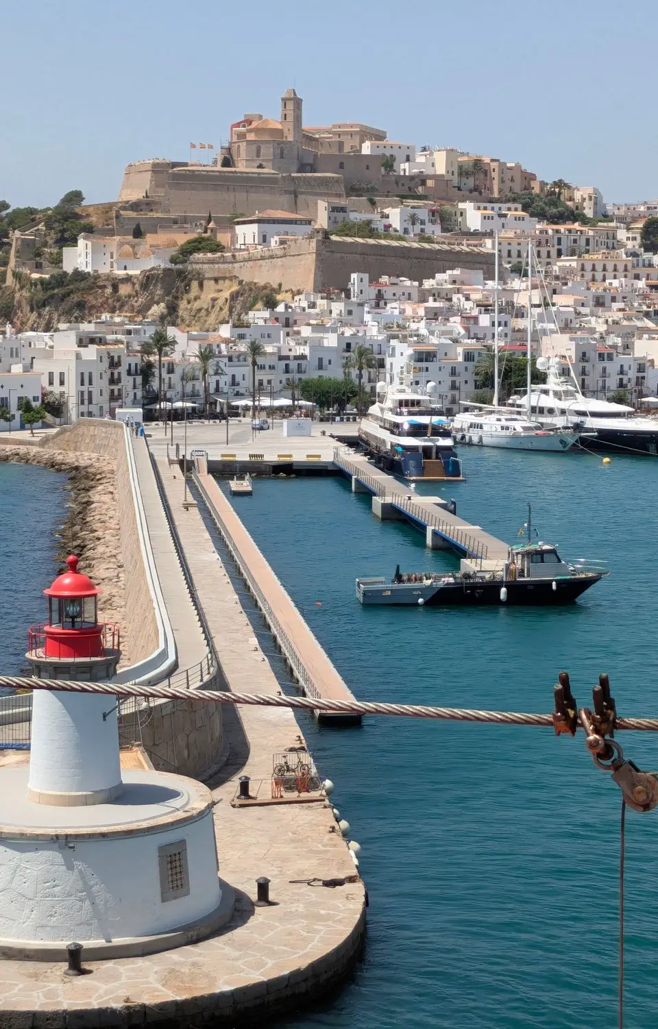 Stunning view of Ibiza harbor featuring a lighthouse with the historic old town in the background.