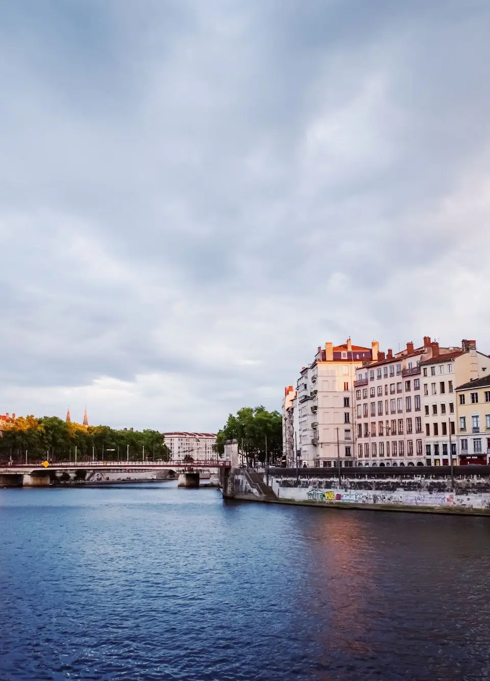Scenic view of colorful buildings reflecting on a Lyon river in the evening light.