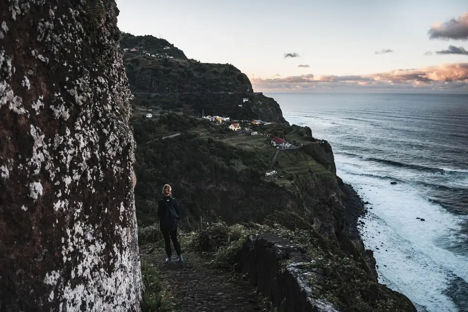 Person walking on a cliffside trail in Madeira, Portugal during the evening.