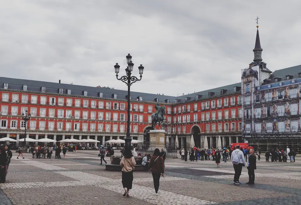 A bustling scene at Plaza Mayor in Madrid featuring the Philip III equestrian statue.