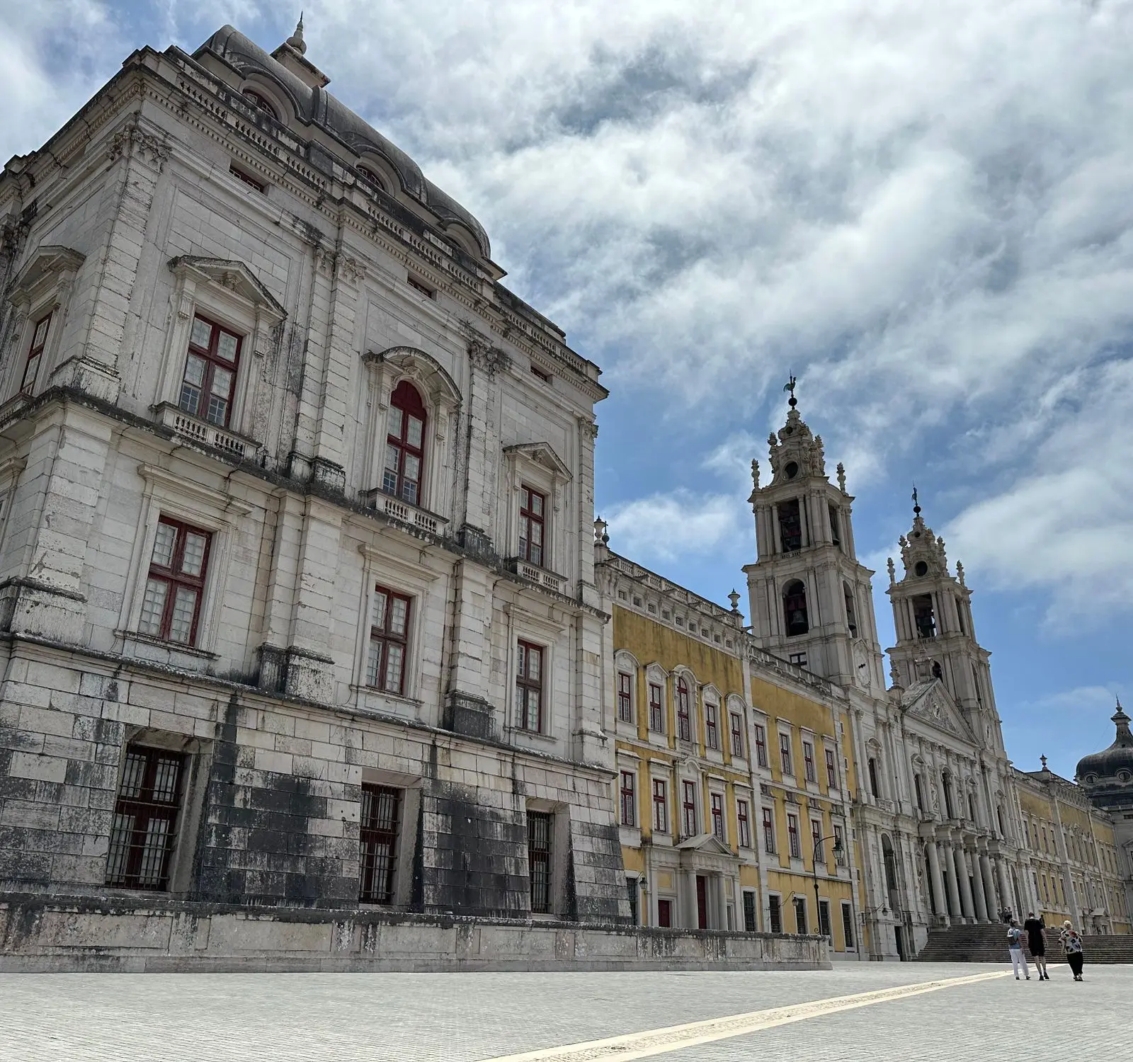 View of the historic Mafra National Palace's intricate facade under a vibrant sky.