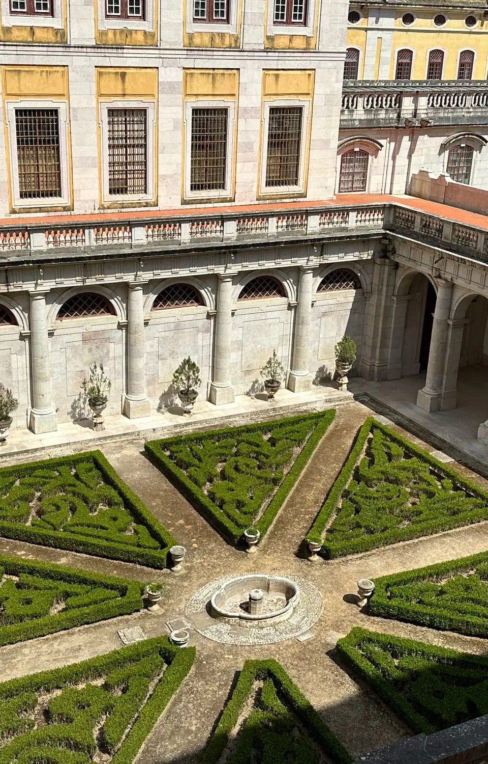 Explore the intricate garden courtyard of Mafra Palace, showcasing classic Portuguese architecture.