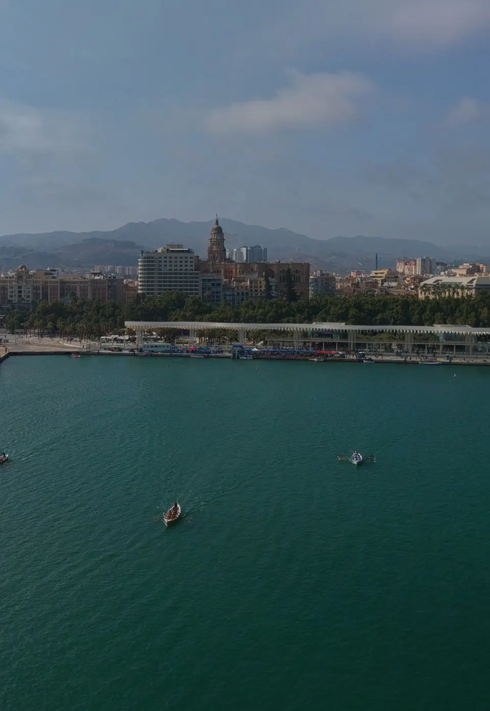 Scenic aerial view of Málaga's harbor and cityscape, showcasing boats on the bay and historic architecture.