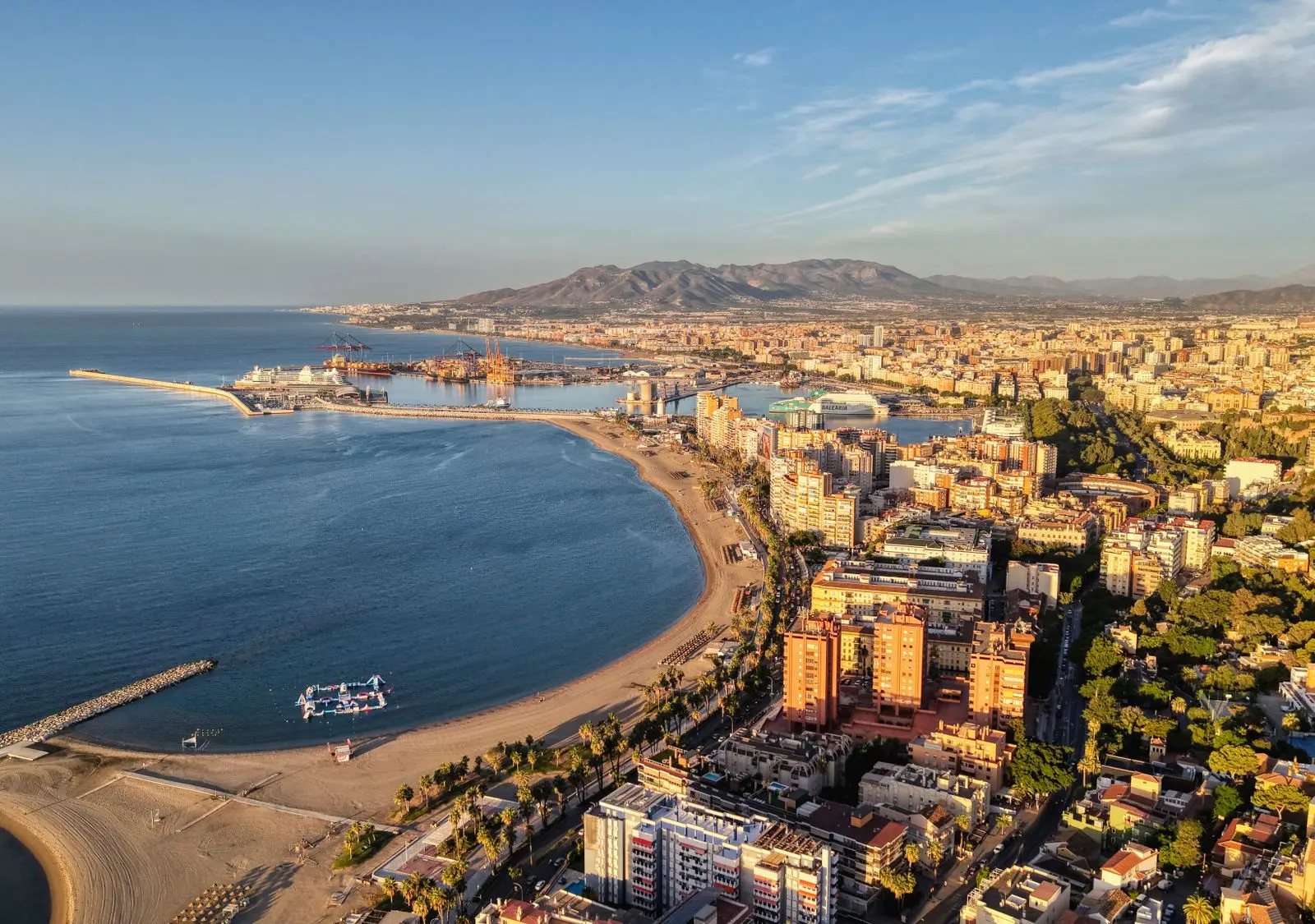 A stunning aerial view of Malaga's coastline and cityscape bathed in sunlight.