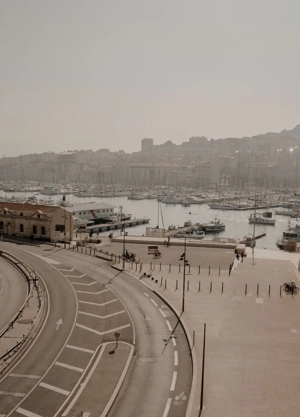 A tranquil view of Marseille's harbor, featuring winding roads, historical architecture, and a serene waterfront.