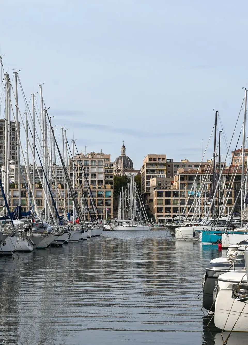 Stunning view of sailboats docked at the Old Port of Marseille with cityscape backdrop.