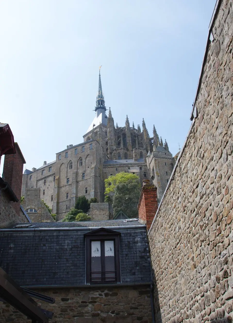 Stone walls frame Mont Saint-Michel Abbey under a clear blue sky.