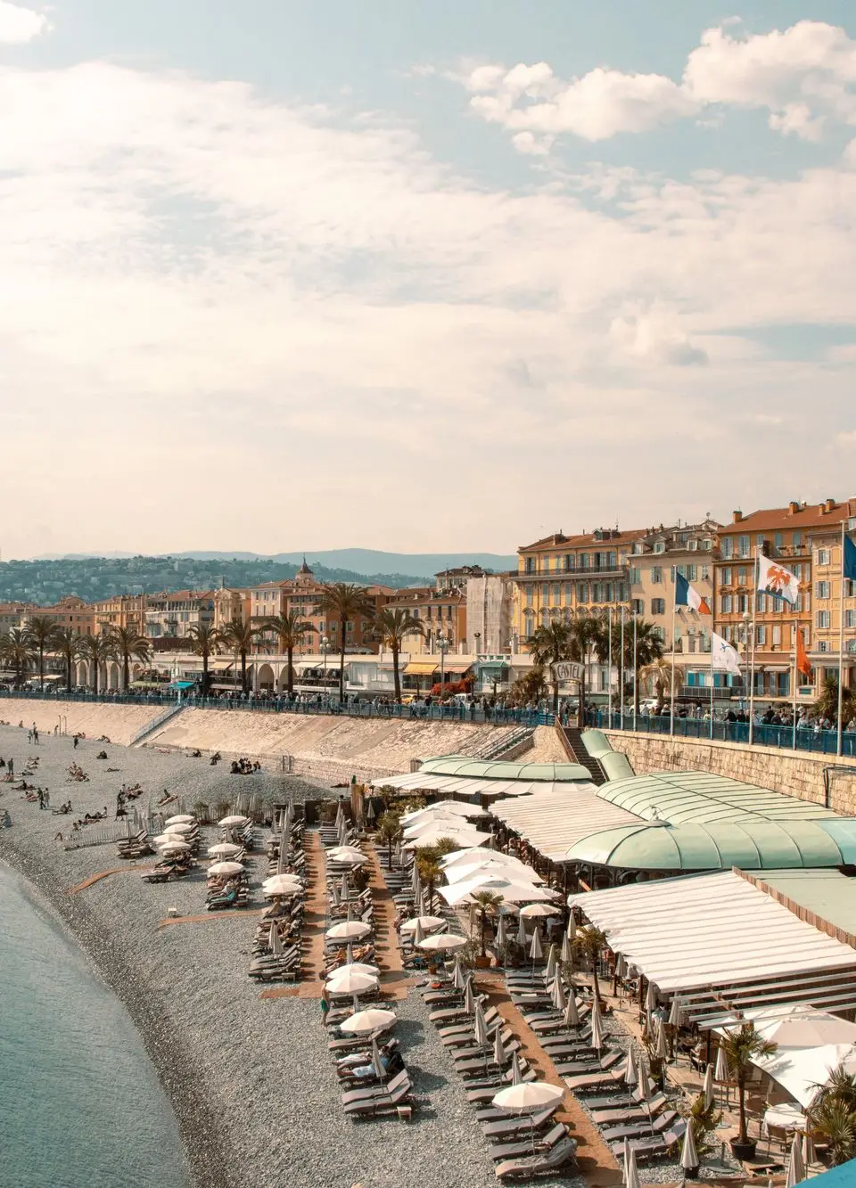 A stunning view of the bustling beach in Nice, France with vibrant buildings and clear skies.