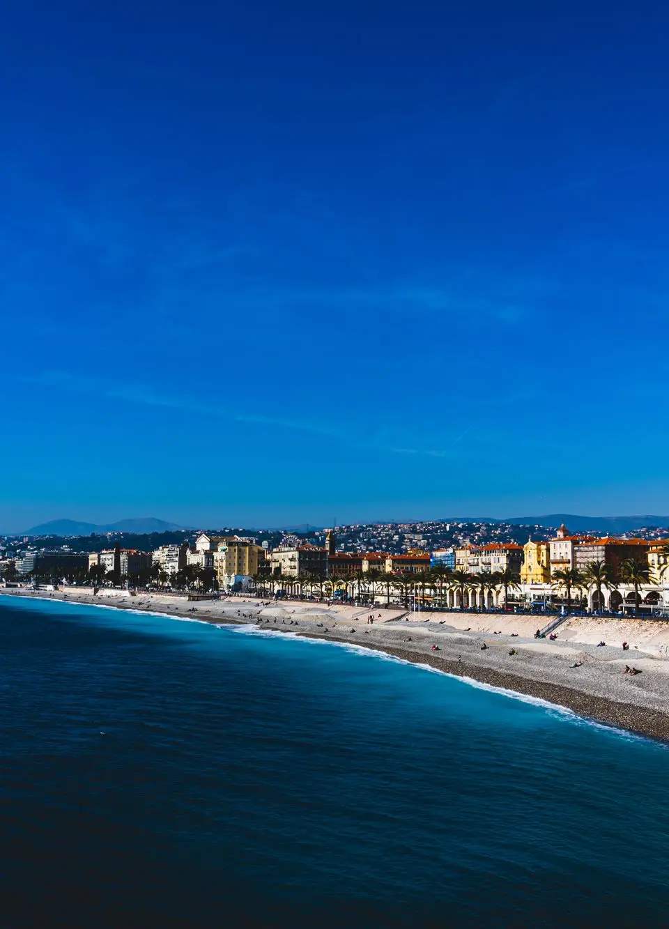 A vibrant beachfront view of Nice, France, capturing the azure waters and colorful architecture on a sunny day.