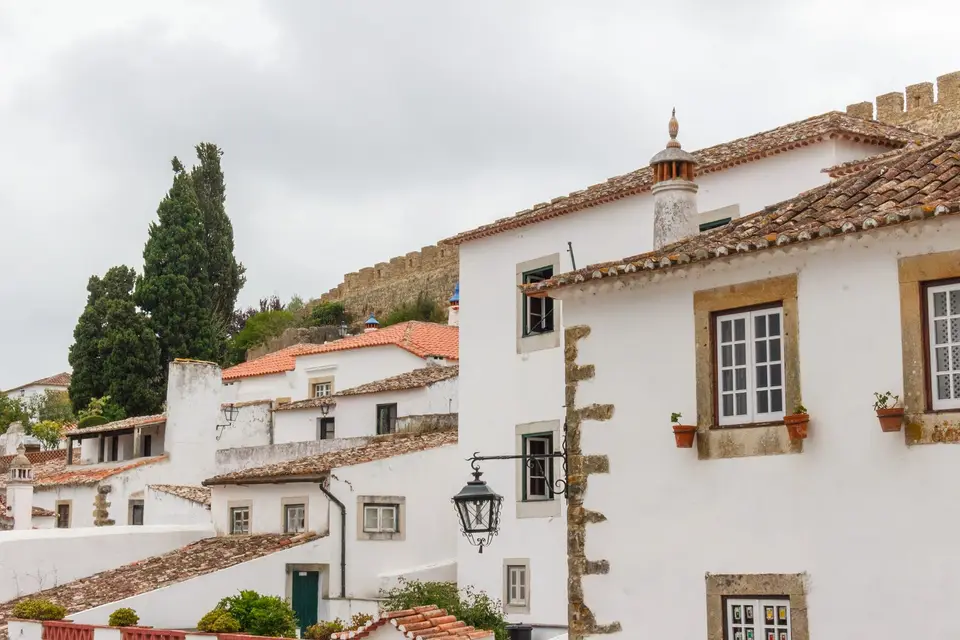 Explore the quaint whitewashed houses and medieval walls of Óbidos, Portugal, captured in this scenic photo.