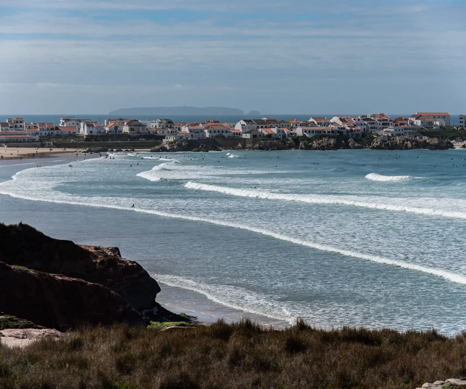 Picturesque view of Peniche's coastline with waves crashing and houses by the Atlantic.