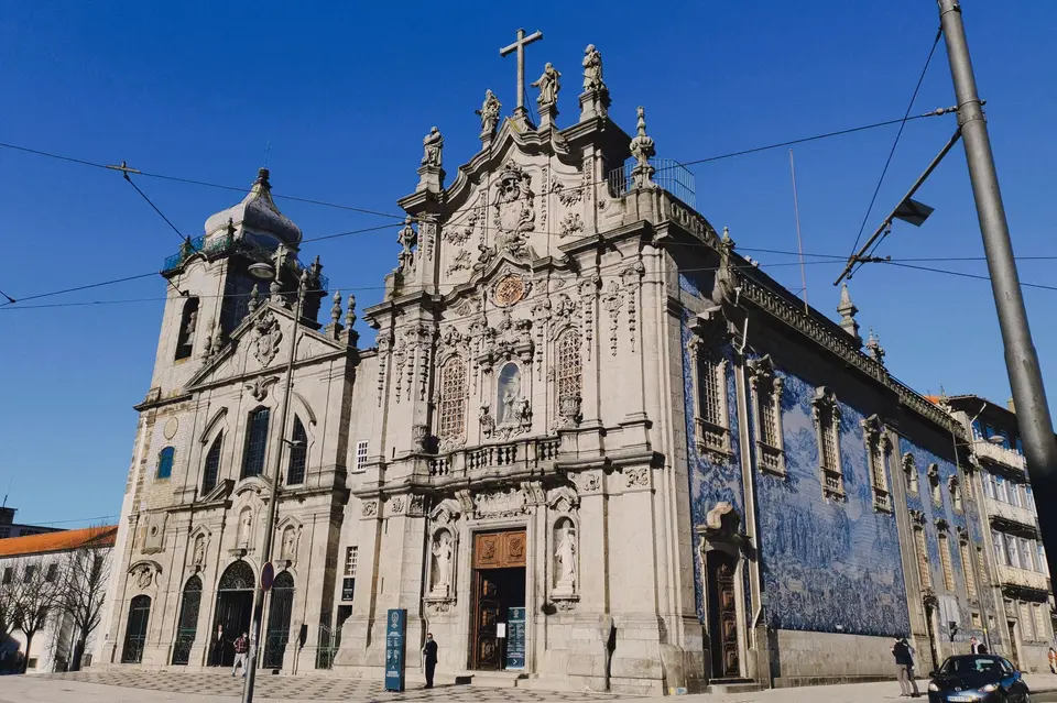 Explore the stunning Baroque facade of Igreja do Carmo in Porto, showcasing intricate azulejo tiles under a clear blue sky.
