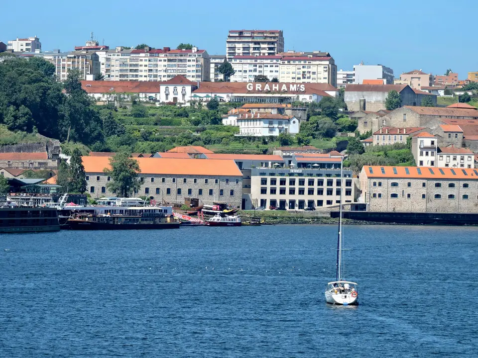 Beautiful view of Porto's waterfront with a sailboat and iconic buildings along the Douro River.