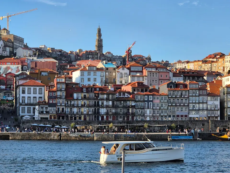 A picturesque view of Porto's historic waterfront with colorful buildings and a boat on the river.