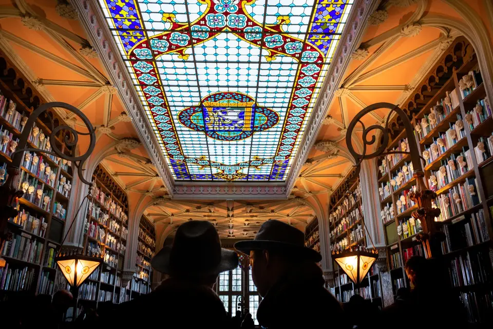 Interior of a Porto bookstore featuring a breathtaking stained glass ceiling and ornate bookshelves.