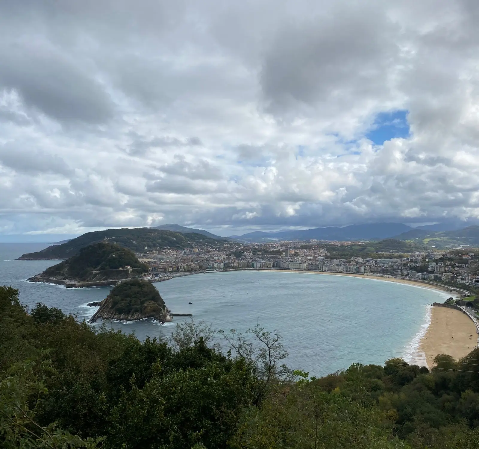 Breathtaking aerial view of the famous La Concha Bay, San Sebastian, showcasing the coastline and cityscape under a cloudy sky.
