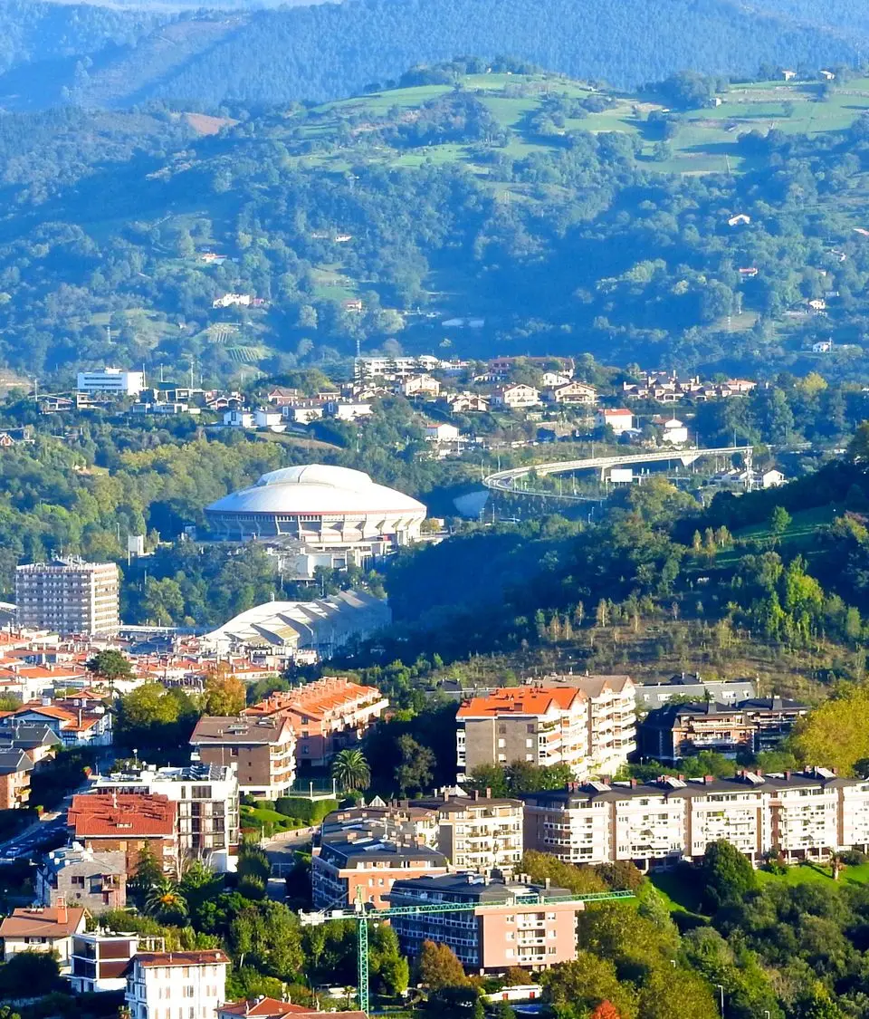 Aerial view of Donostia-San Sebastián with scenic hills and city buildings.