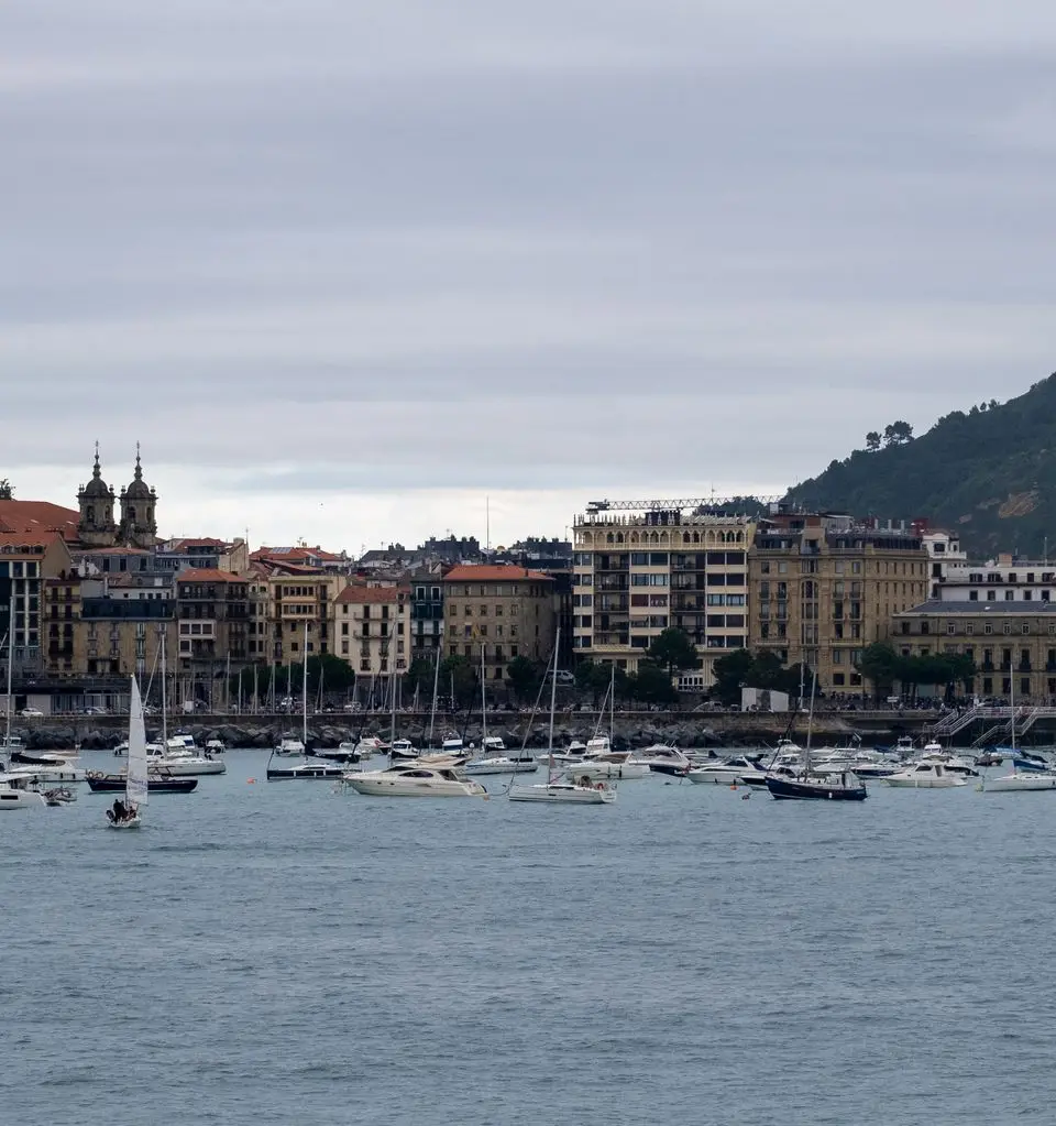 Boats anchored in the picturesque harbor of San Sebastián with a backdrop of historic buildings.