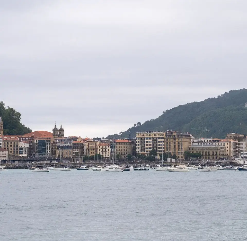 Panoramic view of San Sebastian's harbor and waterfront with boats and hills.