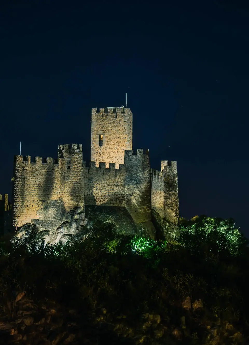 A captivating view of Almourol Castle lit up against the night sky in Portugal.
