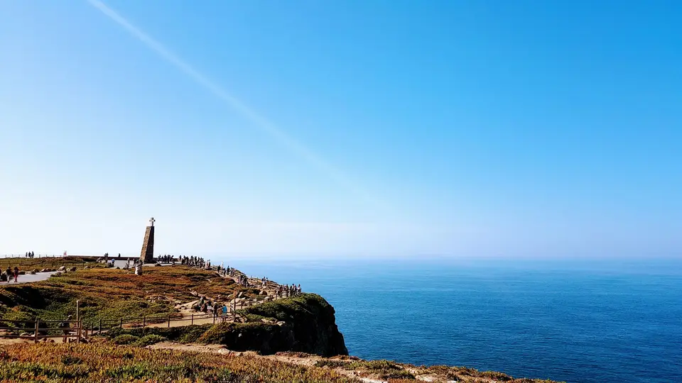 Breathtaking view of Cabo da Roca's rocky cliffs and ocean under a bright blue sky in Portugal.